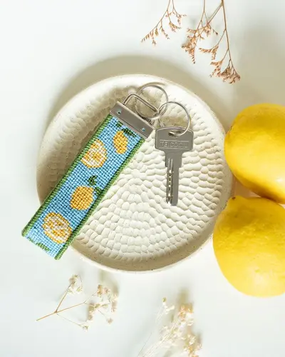 A lemon-print keychain holding keys, on a plate